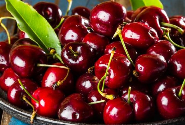 Fresh cherry on black plate on wooden blue background